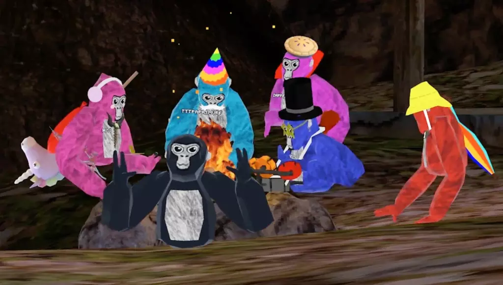 Несколько виртуальных обезьян в костюмах сидят у костра в игре Gorilla Tag VR, окружённые праздничными аксессуарами.
